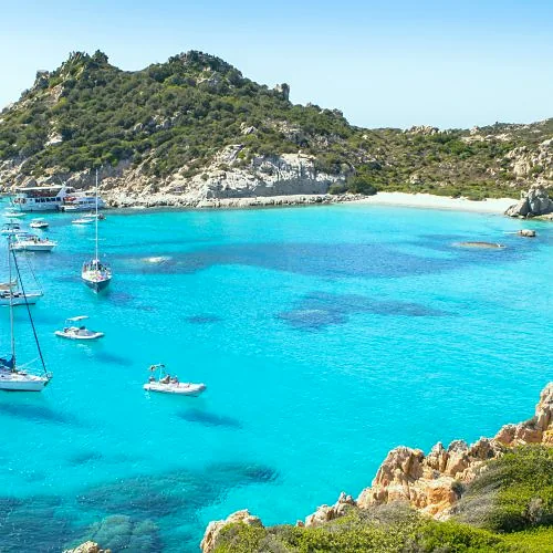 Cala turchese con barche nella Sardegna orientale